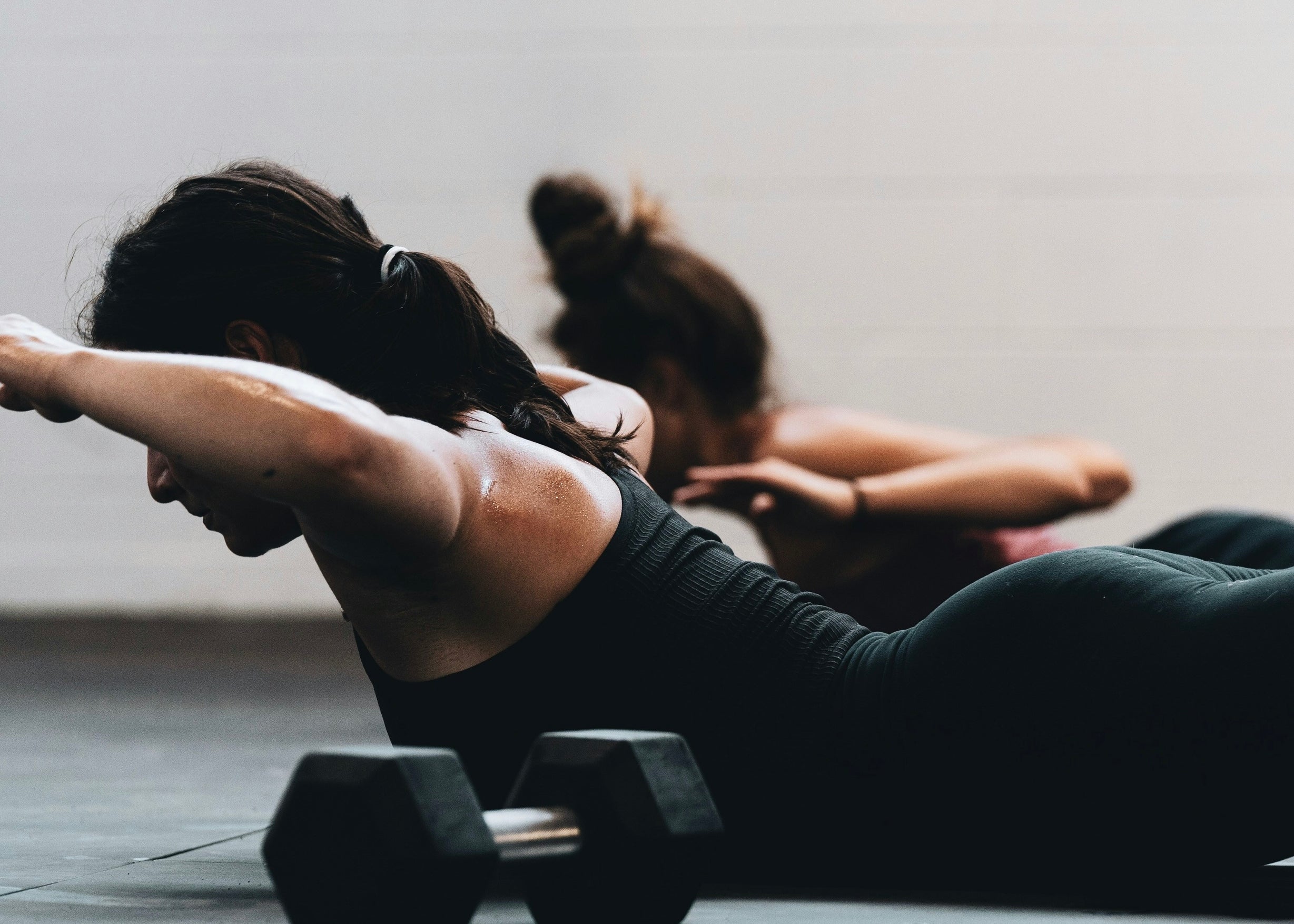 Women doing back-extension exercises with dumbbells — resistance training to protect muscle on GLP-1