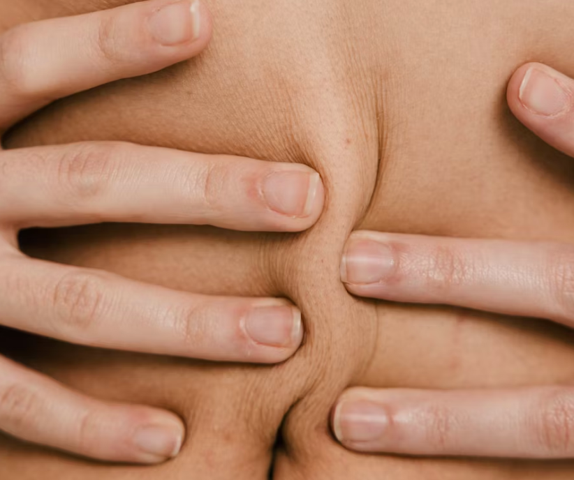 Close-up of hands holding skin at the waist — perimenopause abdominal weight gain