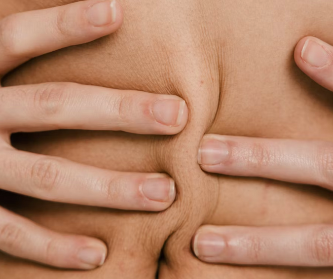 Close-up of hands holding skin at the waist — perimenopause abdominal weight gain